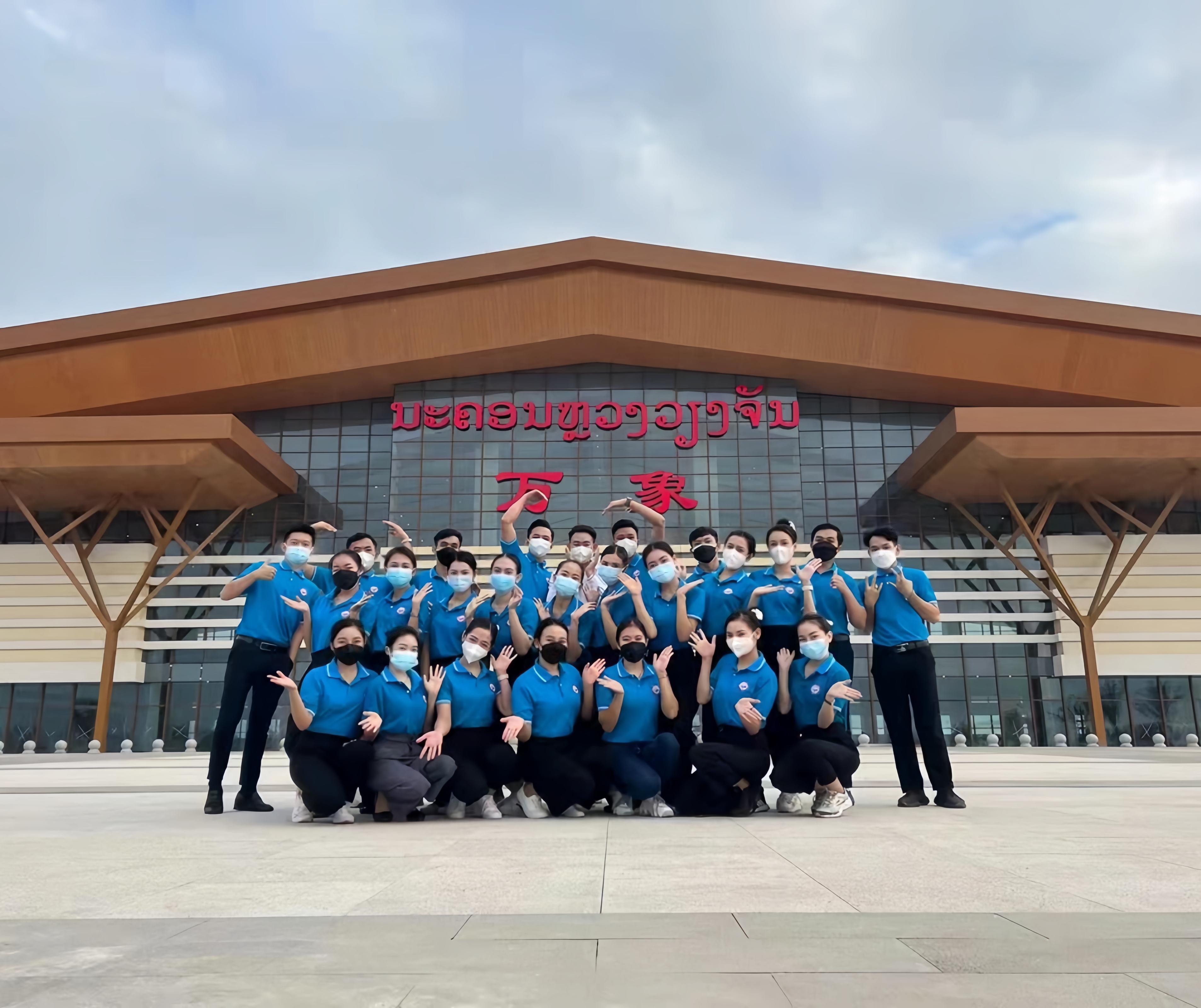 學(xué)生上崗前在老撾萬(wàn)象高鐵站前合影（其中5人為貴陽(yáng)職業(yè)技術(shù)學(xué)院培訓(xùn)班學(xué)生）。 貴陽(yáng)職業(yè)技術(shù)學(xué)院供圖